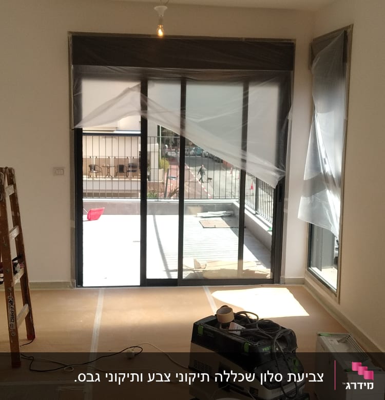 חדר עם ציוד לצביעה, דלי צבע וסולם